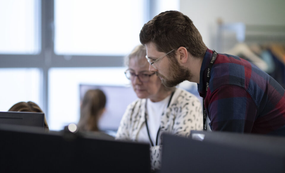 Two caseworkers examine the details of a case on screen, both looking intently.